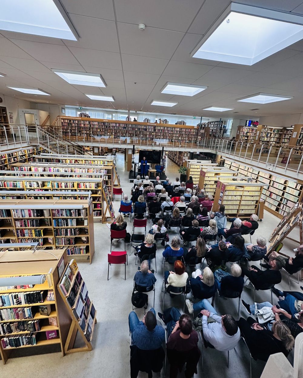 Publiken vid ett författarbesök på Eskilstuna stadsbibliotek, sedd från läktaren.